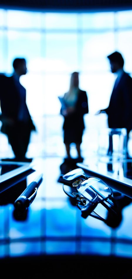 glasses-pen-with-silhouettes-executives-background